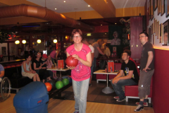 Foto 6: Hier sind Menschen beim Bowling und ein junger Frau hält die Bowlingkugel in der Hand