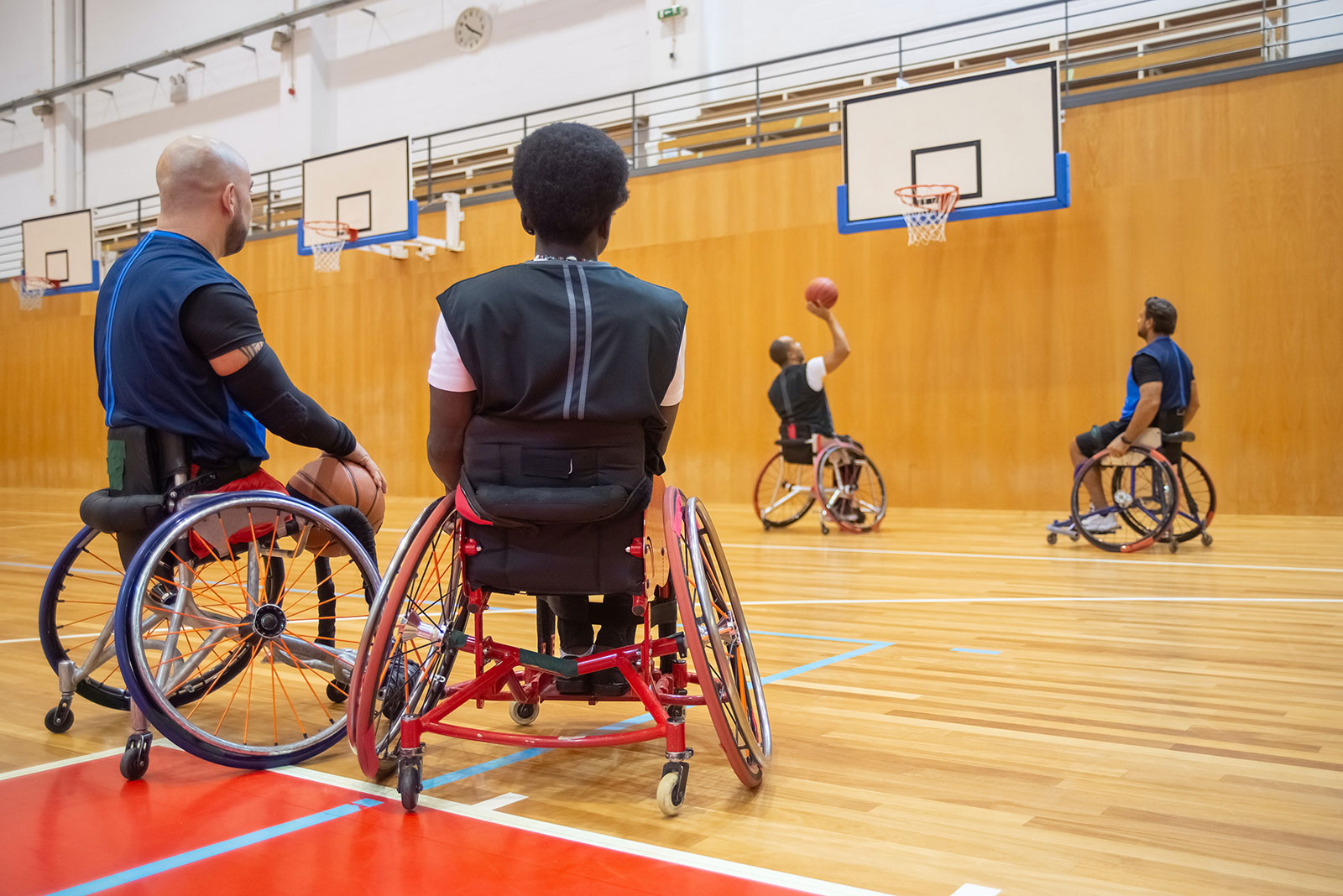 Männer spielen Rollstuhlbasketball in einer Halle